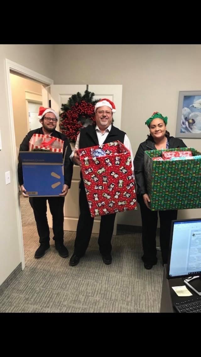 Three volunteers with large boxes filled with gifts for drop off
