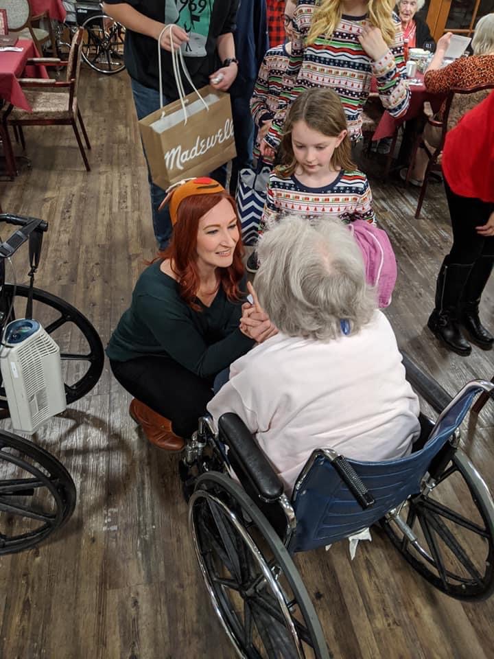 Volunteer woman and child talking with an elderly woman in a wheelchair
