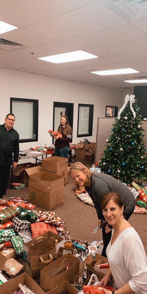 Many volunteers assembling gift bags at an office wrapping party