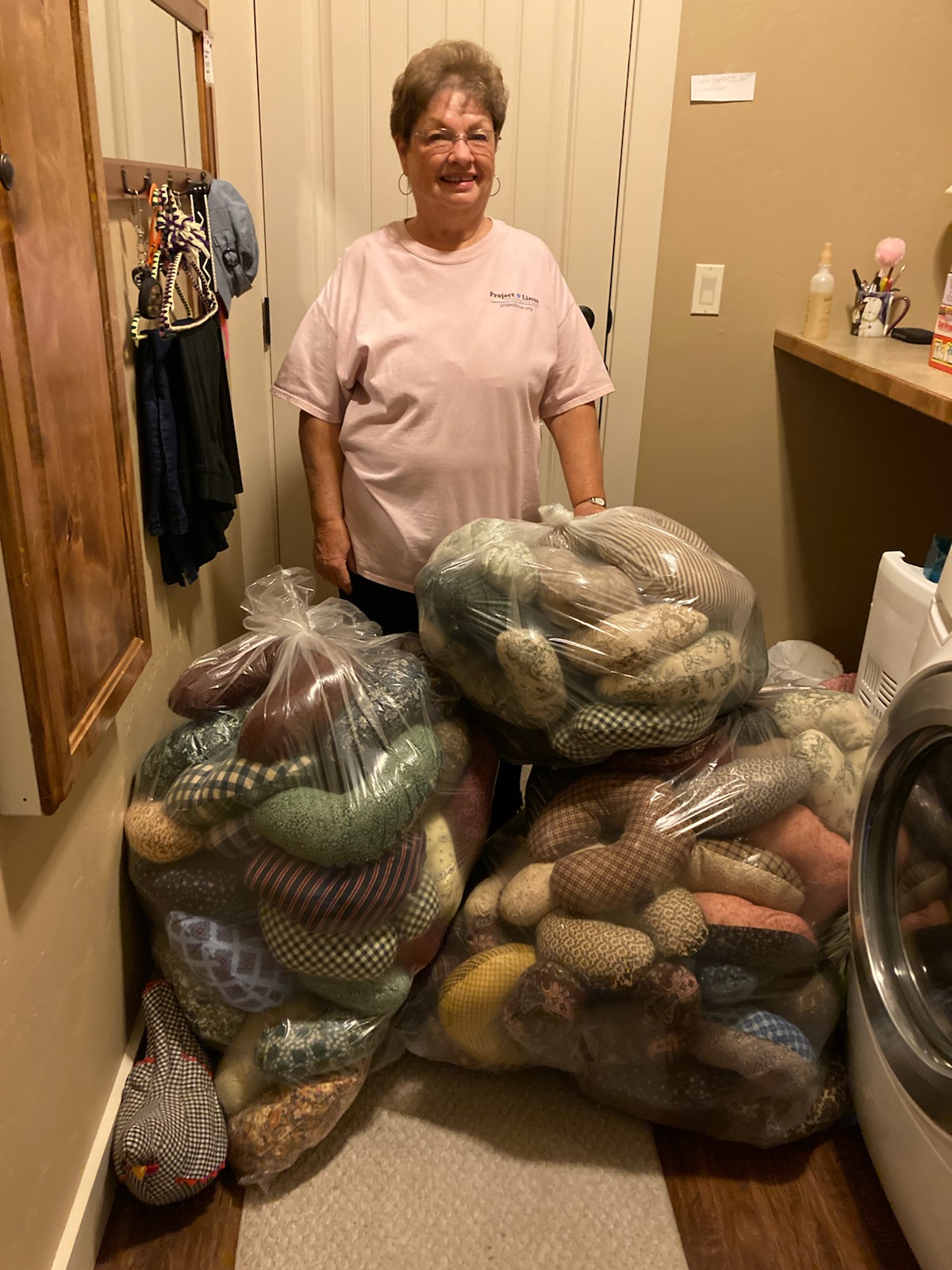 Volunteer posing with large bags filled with neck pillows for donation
