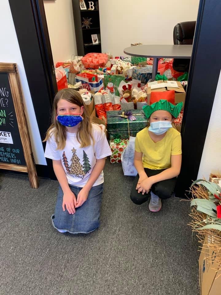 Two young kids in masks guarding a room filled with gifts for donation