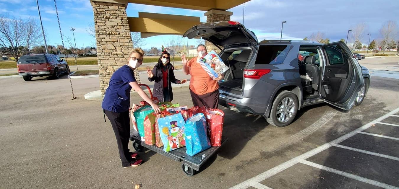 Facility worker loading gift bag donations onto a trolley with volunteers